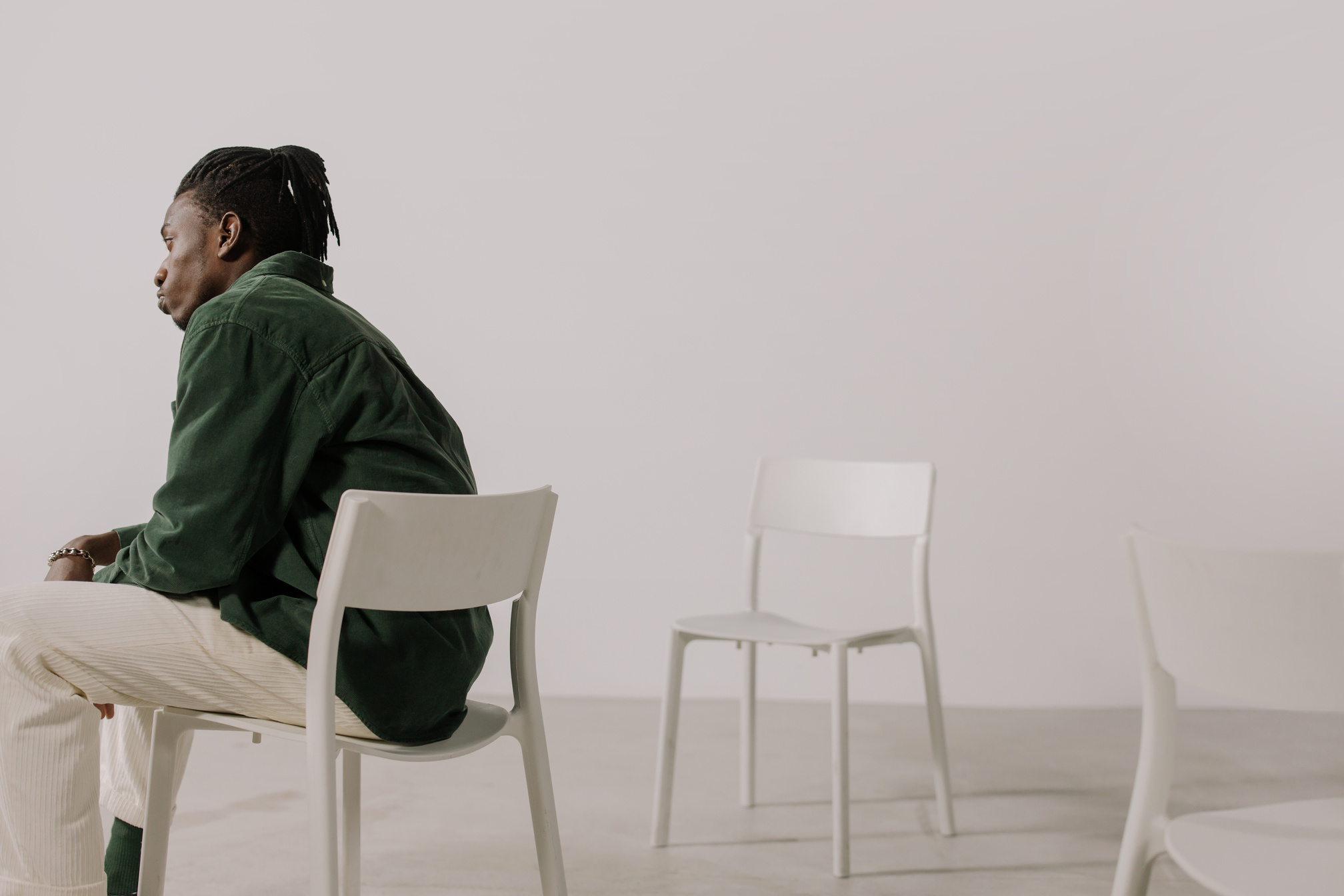 A Person in Green Long Sleeve Shirt Sitting on White Chair